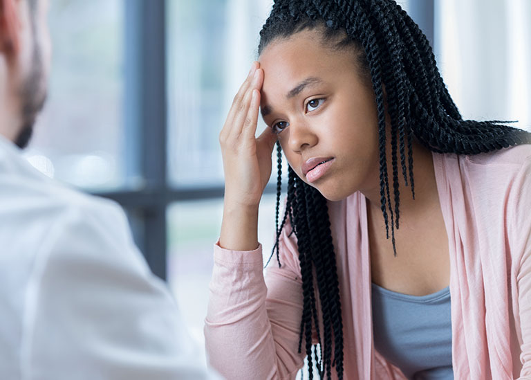 teenage girl listens to physician's migraine treatment